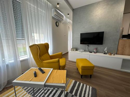 sala de estar con silla amarilla y TV en GOX Apartman, en Subotica
