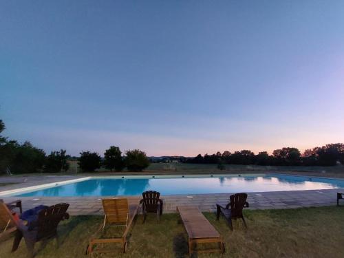 a swimming pool with chairs and a table in front of it at Tenuta La Fratta in Sinalunga