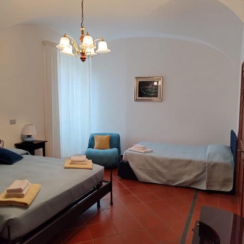 a bedroom with two beds and a chair and a chandelier at La Piazzetta Alloggio Turistico in Canino