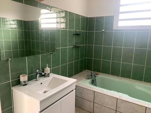 Baño de azulejos verdes con lavabo y bañera en Villa les Poinsettias en Saint-Pierre