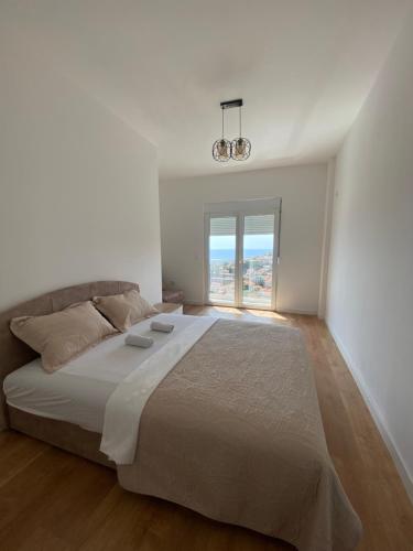 a white bedroom with a large bed and a window at Apartments Radoman in Ulcinj