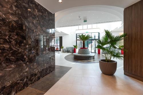 a lobby with potted plants and a stone wall at HOTEL CRYSTAL WELLNESS & SPA superior in Sovata