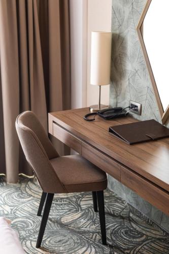 a desk in a hotel room with a lamp and a chair at HOTEL CRYSTAL WELLNESS & SPA superior in Sovata