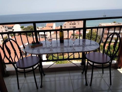 un tavolo con 2 sedie e bicchieri da vino su un balcone di Makis Studios & Apartments a Póros