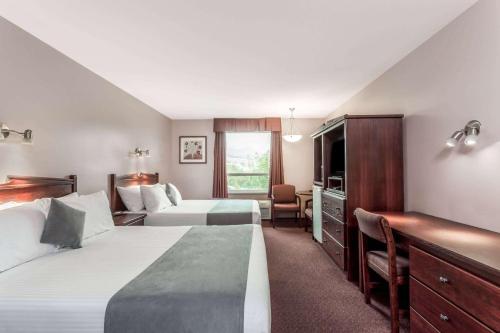 a hotel room with two beds and a desk at Super 8 by Wyndham Lake Country/Winfield Area in Winfield