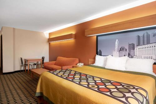um quarto de hotel com uma cama grande e uma cadeira em Super 8 by Wyndham Columbus West em Columbus