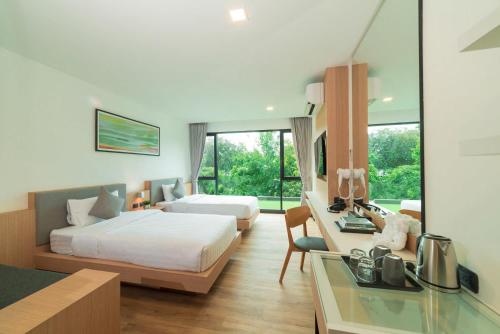 a hotel room with two beds and a desk at Pause and Play Hotel in Chiang Mai