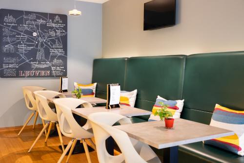 una sala da pranzo con tavoli, sedie e lavagna di ibis Leuven Centrum a Lovanio