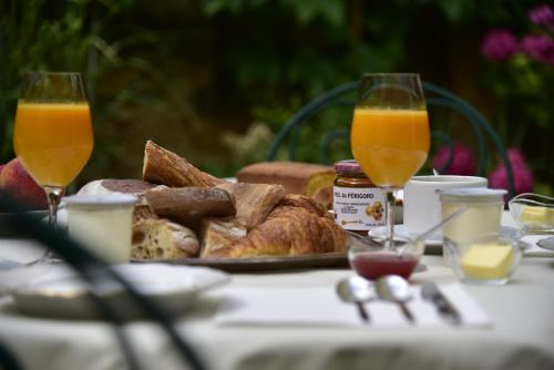 a table with a plate of bread and two glasses of orange juice at Le Clement V in Belvès
