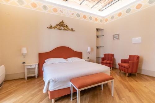 a bedroom with a large white bed and two chairs at Casa Isolani Luxury Rooms Piazza Maggiore in Bologna