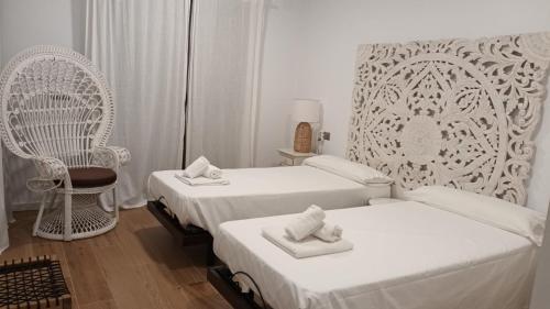 Biały pokój z 2 łóżkami i krzesłem w obiekcie The Links II 2337 Luxury Sea View Apartment w mieście La Alcaidesa