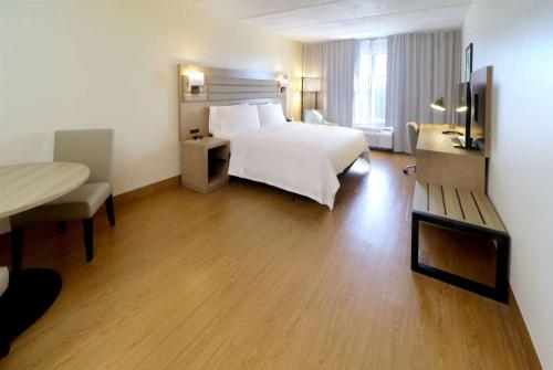 een hotelkamer met een wit bed en een bureau bij Wyndham Garden McAllen at La Plaza Mall in McAllen