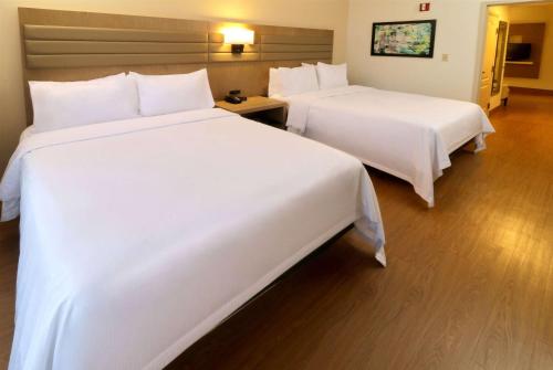 two beds in a hotel room with white sheets at Wyndham Garden McAllen at La Plaza Mall in McAllen