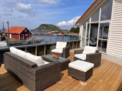 a deck with wicker chairs and a table on a house at Korshamn Rorbuer in Lyngdal