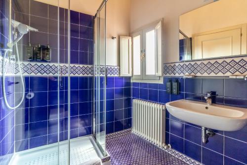 a blue tiled bathroom with a sink and a shower at Casa Isolani Charms Rooms Santo Stefano in Bologna