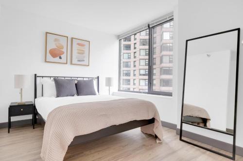a white bedroom with a large bed and a window at Streeterville Studio w Deck Pool nr Beach CHI-583 in Chicago