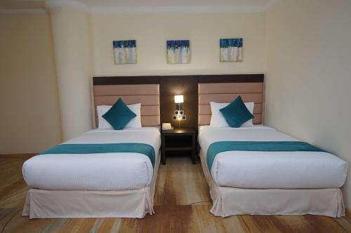 two beds in a hotel room with blue pillows at Best Western Premier Dynasty in Addis Ababa