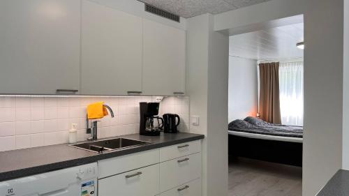 una cocina con fregadero y una cama en una habitación en Tunnelmallinen puutalohuoneisto. en Turku