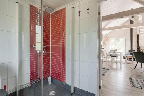 y baño con ducha de cristal y azulejos rojos. en Seaside holiday home in Axmar north of Gavle, en Bergby