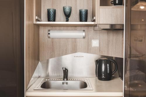 a kitchen with a sink and vases on shelves at Pierros Hotel in Laganas