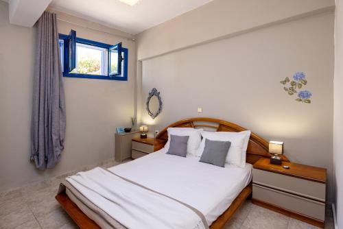a bedroom with a bed with white sheets and a window at Tinos 2 bedrooms 5 persons apartment by MPS in Khatzirádhos