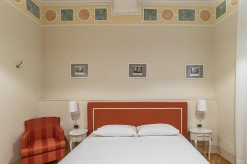 a bedroom with a bed and a red chair at Casa Isolani Luxury Rooms Piazza Maggiore 1 in Bologna