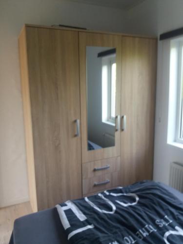 een slaapkamer met een grote kast met een spiegel bij Vakantie Huisje nabij Leeuwarden en Friese kust in Dronrijp