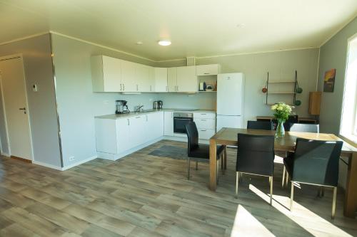 a kitchen with white cabinets and a table and chairs at Senja Fjordhotell and Apartments in Stonglandseidet