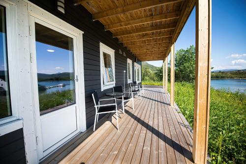 a porch of a house with chairs and a table at Senja Fjordhotell and Apartments in Stonglandseidet