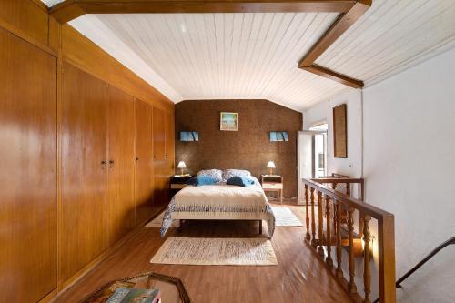 1 dormitorio con 1 cama y pared de madera en Casa Sol e Mar, en Colares