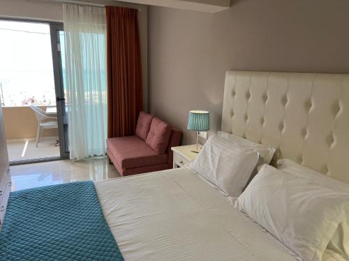 a bedroom with a bed and a chair and a window at Agios Gordios Beach Resort in Agios Gordios