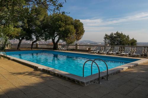 a swimming pool with chairs and trees and a fence at Hotel El Castell in Sant Boi del Llobregat