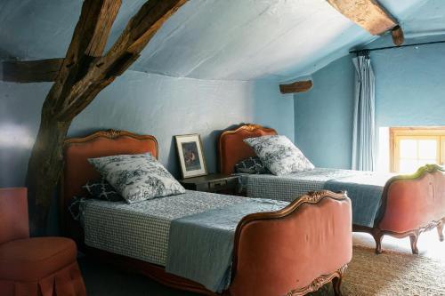 deux lits dans une chambre aux murs bleus dans l'établissement Petite Maison de Gouyas, à Montagrier