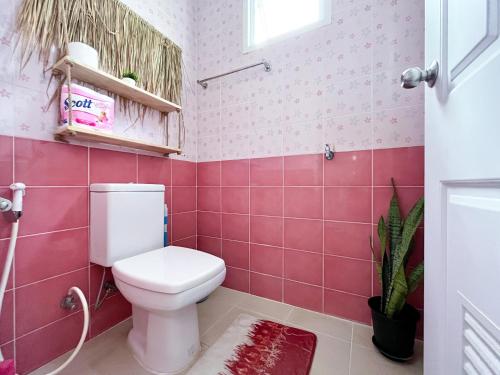 a bathroom with a toilet and pink tiles at Panwa beachfront apartments in Ban Ao Makham