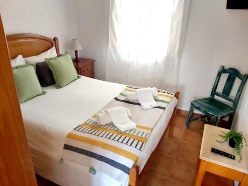 a bedroom with a bed and a green chair at Mateus Studios & Apartments - Duna Parque Group in Vila Nova de Milfontes