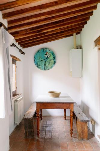 a table and benches in a room with a clock on the wall at Agriturismo Quarantallina in Buonconvento