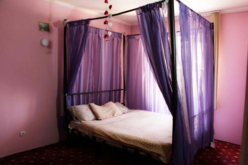 a bedroom with a canopy bed with purple curtains at Аренда дома in Durleşti