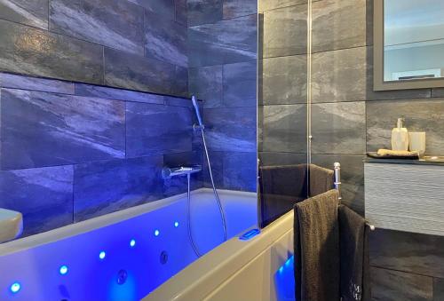 a bathroom with a blue tub and a sink at La Maison de Manolie in Courcelles-Sapicourt