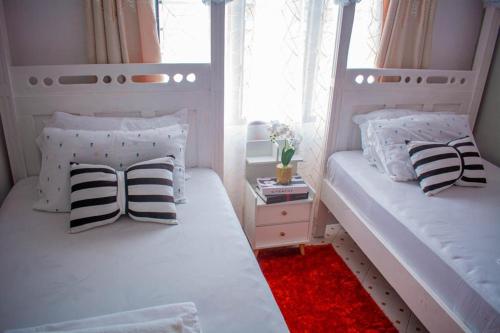 a bedroom with two beds with pillows and a red rug at Emap Homes-serenity hse in Kilifi