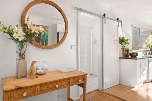 a bathroom with a mirror and a wooden table with flowers at Gretel Cl 4 Nelson Bay in Nelson Bay