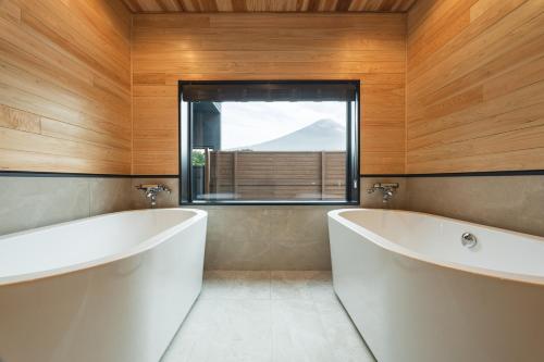 a bathroom with two white tubs and a window at Fuji no Sato Alibio in Fujikawaguchiko