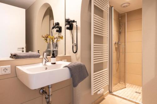 a bathroom with a sink and a shower at Hotel Tide42 in Borkum