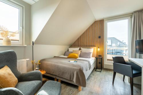 a bedroom with a bed and a desk and two chairs at Hotel Tide42 in Borkum