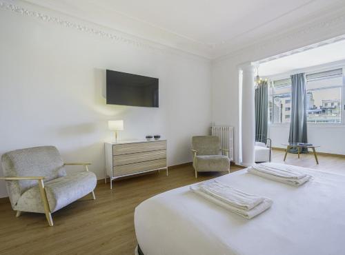 um quarto branco com uma cama, uma cadeira e uma televisão em SibsBcn-PaseodeGracia Luxury Exclusive Gaudi em Barcelona