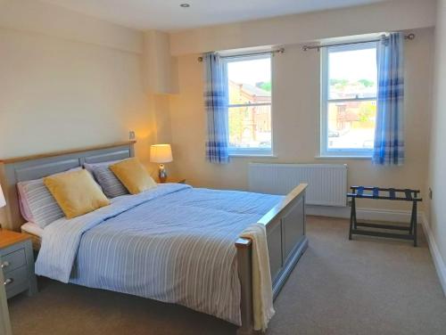 um quarto com uma cama grande e 2 janelas em Barchester House Apartments Delux em Salisbury
