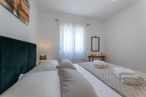 a white bedroom with a bed with towels on it at Treno, Luxurious Apartment with Jacuzzi and Sea-View in Trogir