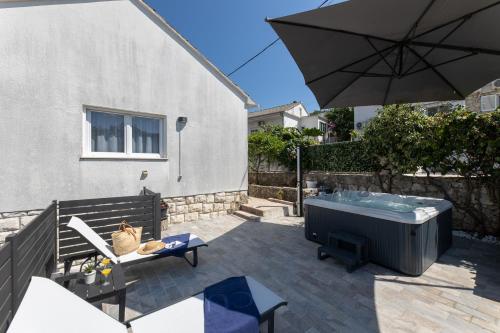 a patio with a hot tub and an umbrella at Treno, Luxurious Apartment with Jacuzzi and Sea-View in Trogir