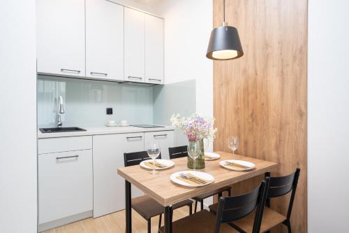 a white kitchen with a wooden table and chairs at Apartamenty Olimpijska by RENT4YOU in Olsztyn