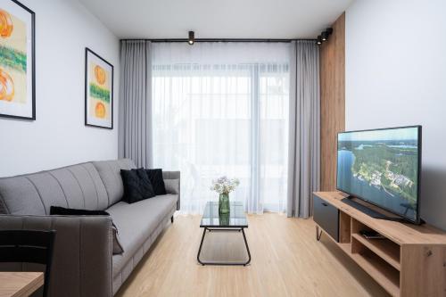 a living room with a couch and a tv at Apartamenty Olimpijska by RENT4YOU in Olsztyn