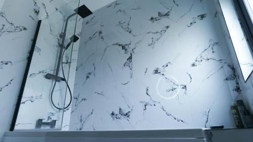 a shower in a bathroom with a white marble wall at Short City Stays in Hunslet